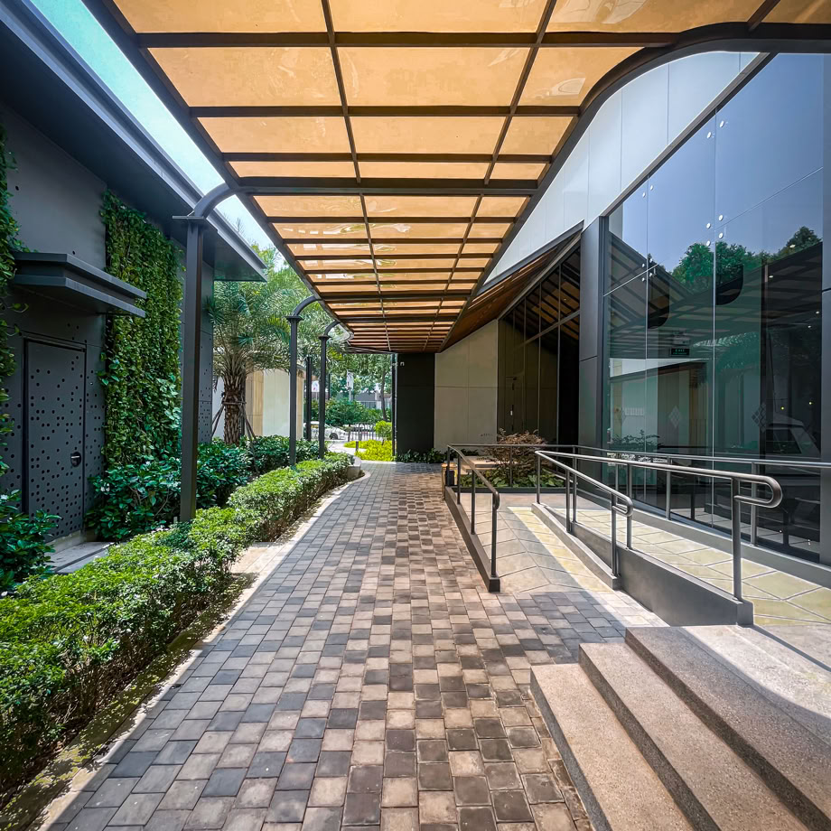 A contemporary walkway with a canopy and lush greenery.